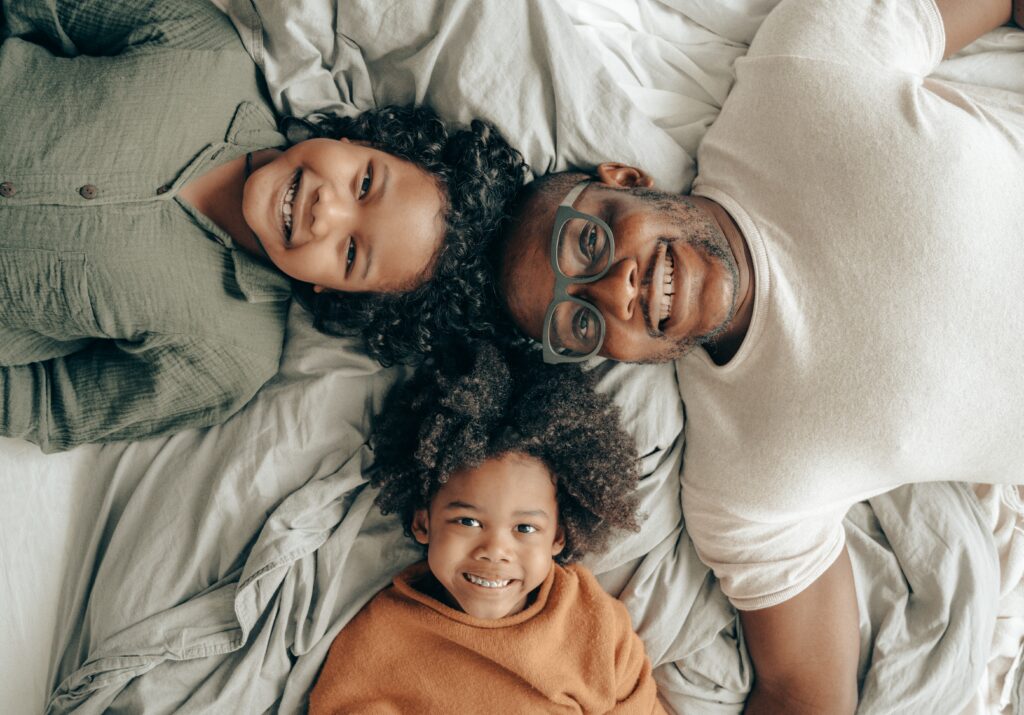 father and two children on bed